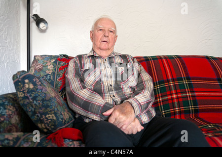 A retired elderly Senior Man in his home sitting on his sofa. Stock Photo