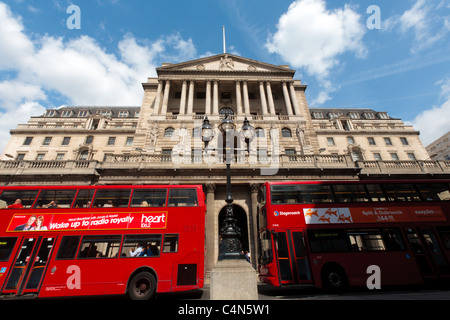 Two red buses pass the Bank of England building in Threadneedle Street, City of London in early morning. Stock Photo