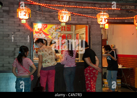 Beijing, China, Group Chinese WOmen Ordering Take Away Food at Snack Bar on Street in Houhai Lake District, at Night, vintage outdoor lights, Chinese old city Stock Photo