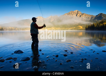 Middle age male fly fishing in Pyramid Lake, Jasper National Park, Alberta, Canada.