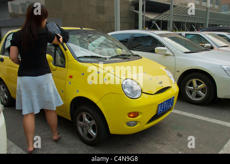 Beijing, China, Chinese Woman Standign from Behind, Outside, Dusting off Air pollution for Car in parking Lot Stock Photo
