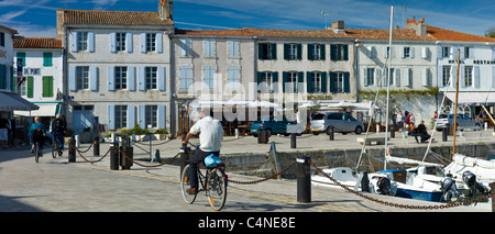 Tourists cycling along the harbour at Quai de Senac in La Flotte, Ile de Re, France Stock Photo