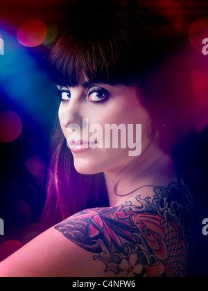 Artistic portrait of a beautiful young woman with a tattoo on the backs