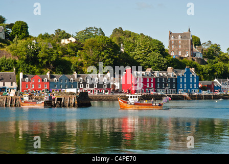 A traditional wooden fishing boat returns home to the colourful harbour town of Tobermory on the Isle of Mull, Scotland Stock Photo