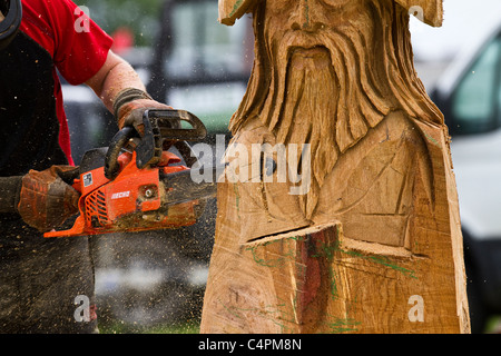Chain Saw carver at the Cheshire Game & Country Fair Show, Knutsford, UK. Wood sculpture, sawdust, sculptor, timber, chips, log, professional, working, art, artist, cut, chain saw, artwork made from rough timber log. Stock Photo
