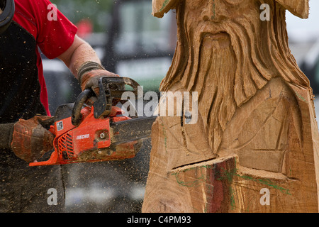 Chain Saw carver at the Cheshire Game & Country Fair Show, Knutsford, UK. Wood sculpture, sawdust, sculptor, timber, chips, log, professional, working, art, artist, cut, chain saw, artwork made from rough timber log. Stock Photo