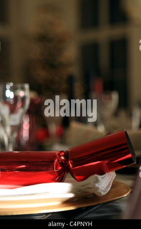 Christmas Cracker resting on napkin and charger at the dinner table Stock Photo