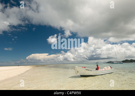 Dramatic clouds above boat on sandy beach in Mamanuca Islands of Fiji Melanesia South Pacific