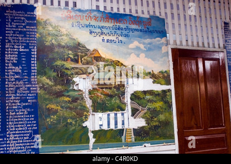 An old sign with a photograph of historic Wat Phu Si Buddhist Temple guides tourists in Luang Prabang, Laos. Stock Photo