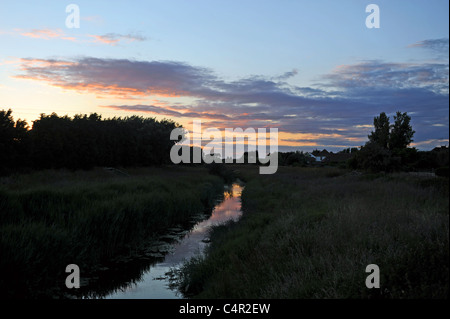 The sun sets over the Rife river which leads into the sea at Ferring near Worthing West Sussex UK Stock Photo