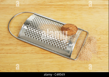 Grated nutmeg and grater on a wooden board Stock Photo
