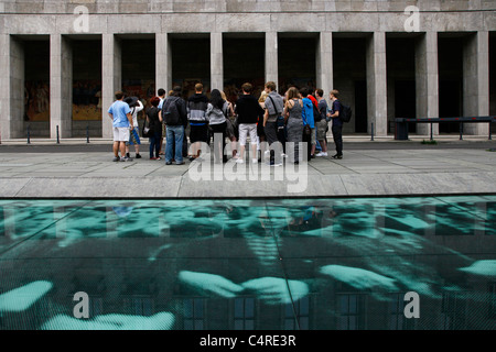 Group of tourists stand across the 17 June Memorial by Wolfgang Rüppel which recalls the events of a popular uprising of 1953 against the communist government in East Germany located in front of the Bundesministerium der Finanzen (Federal Ministry of Finance), which was the Haus der Ministerien (House of Ministries), the seat of the East German government. on Leipziger Strasse in Berlin, Germany Stock Photo