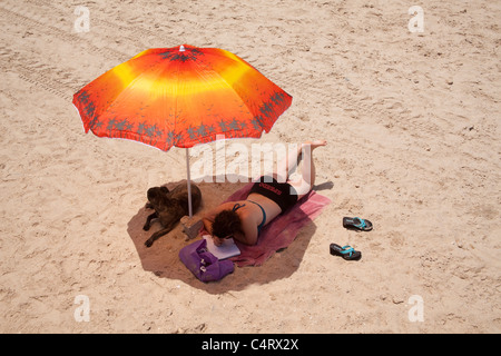 young woman working on Tel Aviv beach under beach umbrella Stock Photo
