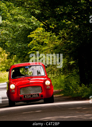 Renovated classic car 1959 Ford Anglia 100E driving in English country lane Stock Photo