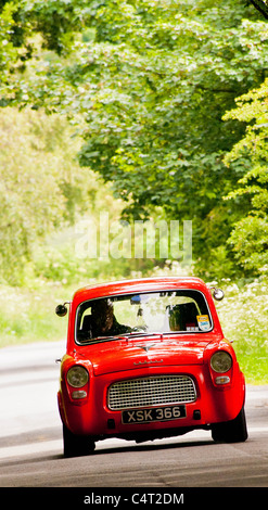 Renovated classic car 1959 Ford Anglia 100E driving in English country lane Stock Photo