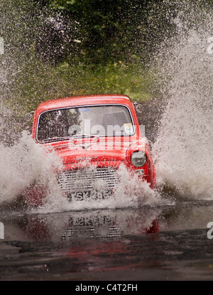 Renovated classic car 1959 Ford Anglia 100E going through water ford Stock Photo