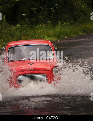 Renovated classic car 1959 Ford Anglia 100E going through water ford Stock Photo