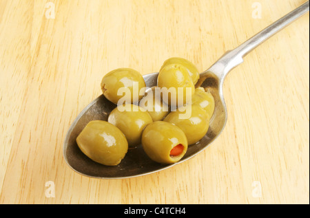 Olives in a silver serving spoon on a wooden board Stock Photo