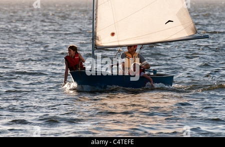 Man and two girls in a sailing dinghy Stock Photo