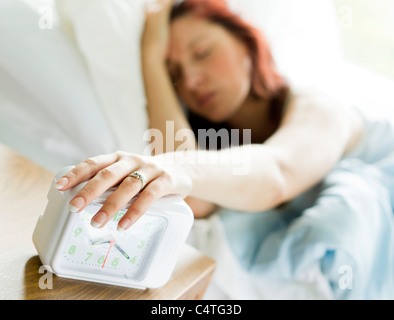 Woman turning off alarm clock Stock Photo