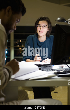 Colleagues working on project together in office at night Stock Photo