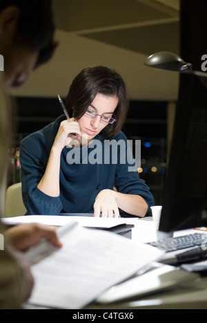 Colleagues reading documents in office at night Stock Photo