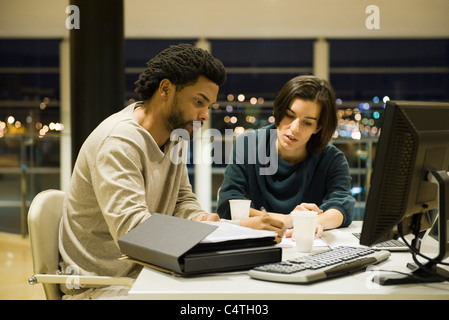 Colleagues working on project together in office at night Stock Photo