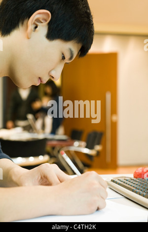 Young man writing at desk Stock Photo