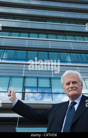 Businessman outside office buildings pointing to something Stock Photo ...