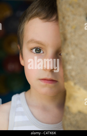 Little boy behind tree trunk, portrait Stock Photo