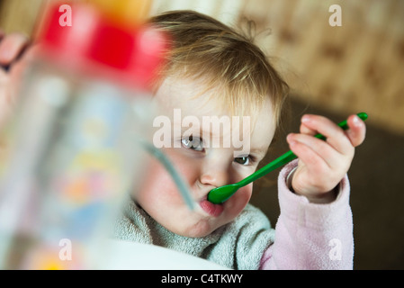 Toddler girl feeding herself with spoon Stock Photo