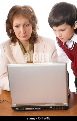 Teacher and schoolboy using computer in class over blackboard. Portrait ...