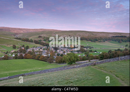 Kettlewell village, nestling in scenic rural valley below upland hills & moors & pink evening sunset sky - Wharfedale, Yorkshire Dales, England, UK.