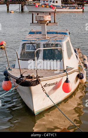 Bridlington harbour in evening sun (small dirty fishing boat moored, calm sea, for sale sign & buoys) - scenic North Yorkshire Coast town, England, UK Stock Photo