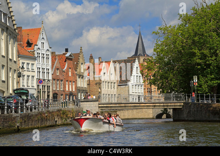 Verversdijk, Bruges, Belgium. Tourist enjoy a tour of the canal in a sightseeing boat. Stock Photo