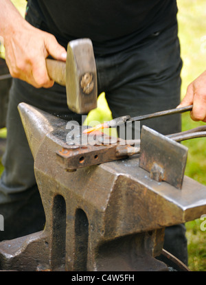 Blacksmith hammering hot iron on anvil - close up Stock Photo