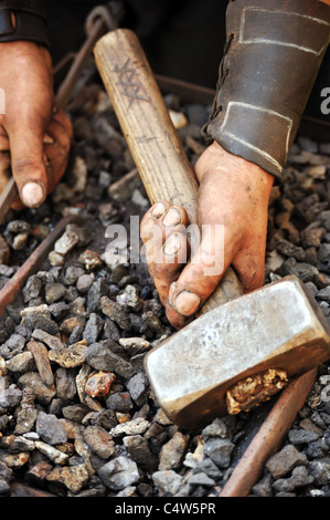 Detail of dirty hands holding hammer - blacksmith Stock Photo