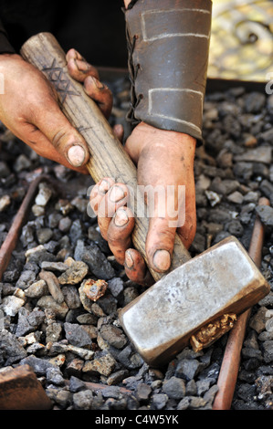 Detail of dirty hands holding hammer - blacksmith Stock Photo