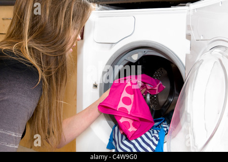 Attractive young Caucasian woman emptying clean washing in from washing machine, taken in Bristol, England, uk Stock Photo