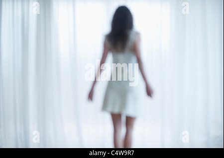 USA, New Jersey, Jersey City, Young woman standing and looking through window Stock Photo