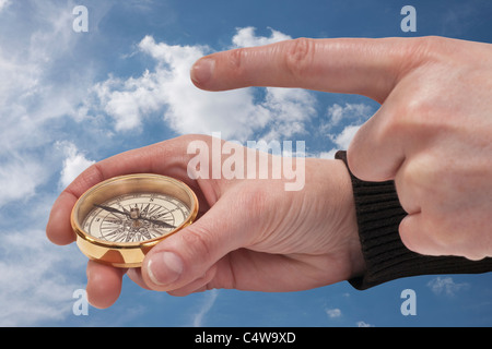 ein Kompass wird in der Hand gehalten, ein Finger zeigt die Richtung | a compass is hand-held, a finger shows the direction Stock Photo