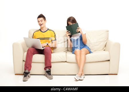 woman with book peaking at boyfriend with laptop Stock Photo