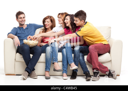 friends sitting on couch reaching for the popcorn bowl  Stock Photo