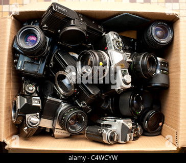 a cardboard box of assorted used old second hand 35mm old film SLR camera bodies and lenses, UK