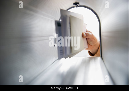 Close-up of man's hand removing letters from letter box Stock Photo