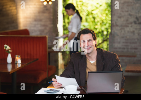 USA,New York,New York City,Owner working with laptop in restaurant with waitress in background Stock Photo