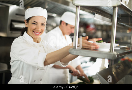 USA, New York State, New York City, Chefs preparing food, woman looking at camera and smiling Stock Photo