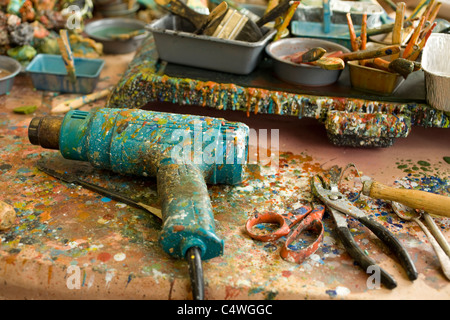 Encaustic artist has tools on her bench, covered with dripped colored wax. Stock Photo