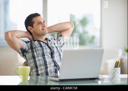 USA, New Jersey, Jersey City, man sitting at desk with hands behind head Stock Photo