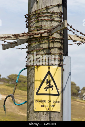 Danger of Death Keep Off sign on electricity pole pylon with barbed wire Stock Photo